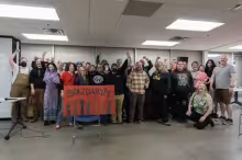 A crowd raises their fists in solidarity, at a fundraiser