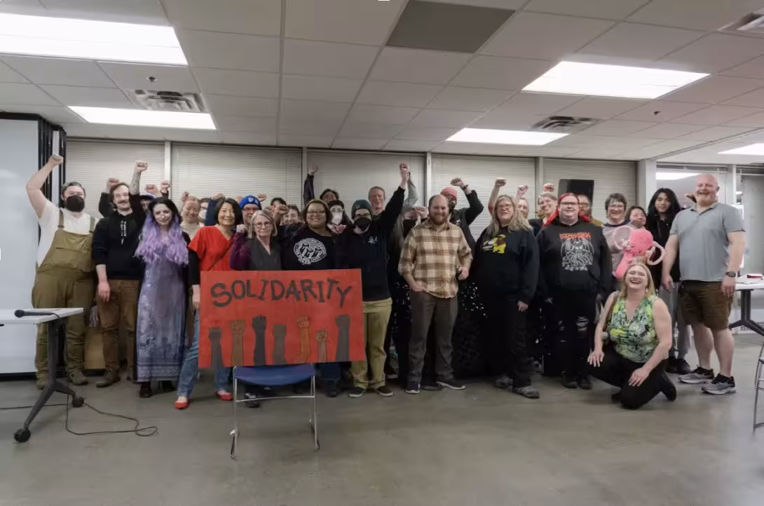 A crowd raises their fists in solidarity, at a fundraiser